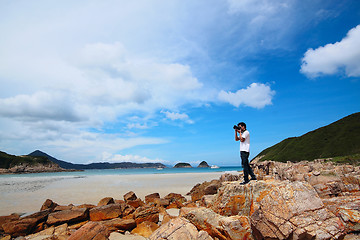 Image showing Portrait of a young man standing on a beach with a camera 