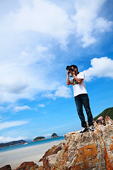 Image showing Portrait of a young man standing on a beach with a camera 