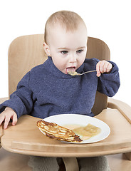 Image showing young child eating in high chair