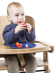 Image showing young child eating in high chair