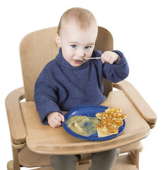 Image showing young child eating in high chair