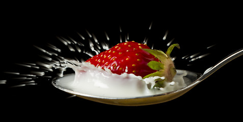 Image showing red, ripe strawberry falling in spoon with milk