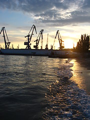 Image showing everning sea with hoisting crane in the seaport