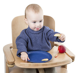 Image showing young child eating in high chair