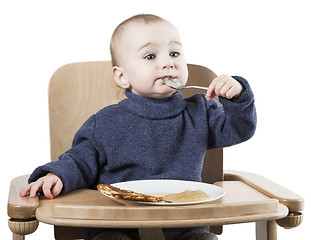 Image showing young child eating in high chair