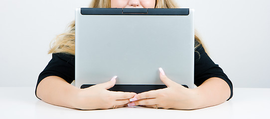 Image showing The girl hides behind an laptop