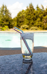 Image showing Glass of water with ice cubes on side of pool