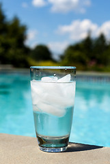 Image showing Glass of water with ice cubes on side of pool