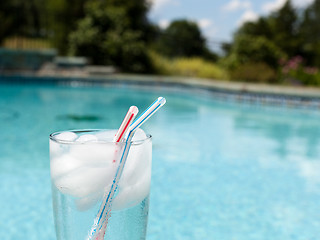 Image showing Glass of water with ice cubes on side of pool