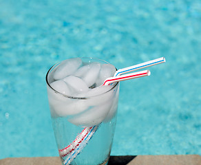 Image showing Glass of water with ice cubes on side of pool