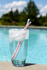 Image showing Glass of water with ice cubes on side of pool