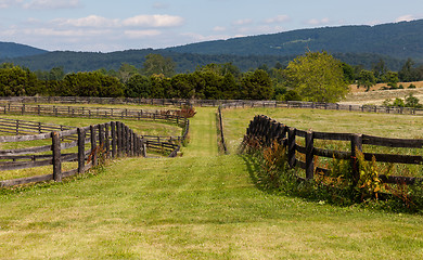 Image showing Rolling meadows with wooden fences and hills