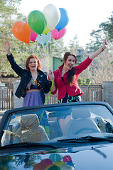 Image showing Two young happy girls with air balloons in cabrio