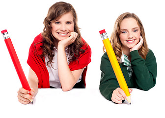 Image showing Beautiful schoolgirls posing with big pencil