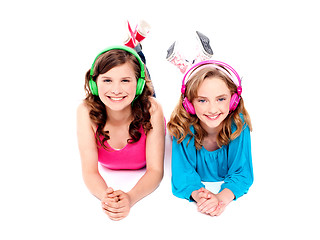 Image showing Two beautiful girls lying on floor wearing headphones