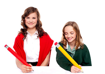 Image showing Cheerful girls writing with pencil on surface