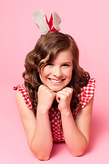 Image showing Happy young girl lying on floor. Hands on chin