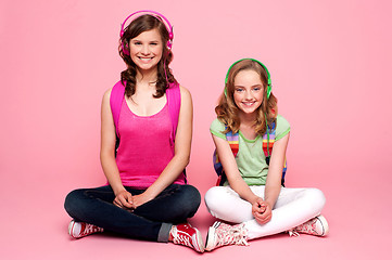 Image showing Two school friends sitting on studio floor