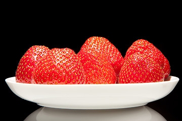 Image showing white saucer with red strawberr on a black background