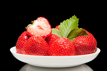 Image showing white saucer with red strawberr on a black background