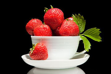 Image showing red strawberry in white cup on a black background