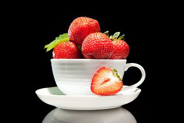 Image showing red strawberry in white cup on a black background