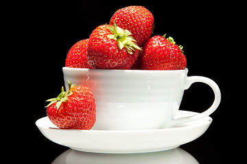 Image showing red strawberry in white cup on a black background