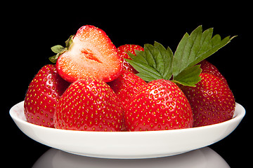 Image showing white saucer with red strawberr on a black background