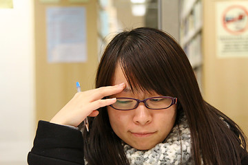 Image showing Asian woman thinking and studying in library