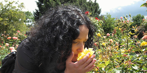 Image showing Pretty brunette smelling roses