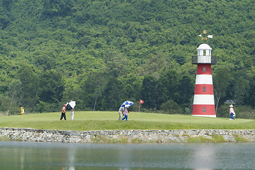 Image showing Golf players and caddies on green