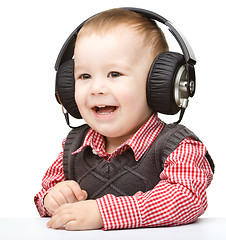 Image showing Cute little boy enjoying music using headphones
