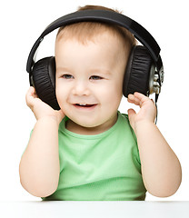 Image showing Cute little boy enjoying music using headphones