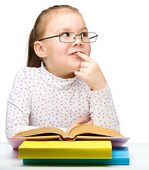 Image showing Cute little girl is dreaming while reading book