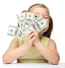 Image showing Cute little girl is covering her eyes with dollars