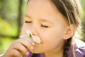 Image showing Portrait of a cute little girl smelling flowers