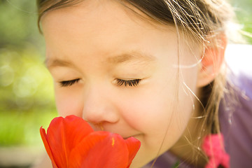 Image showing Portrait of a cute little girl smelling flowers