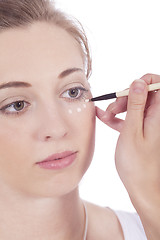 Image showing young beautiful woman applying concealer on face