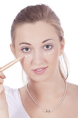 Image showing young beautiful woman applying concealer on face