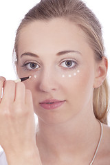 Image showing young beautiful woman applying concealer on face