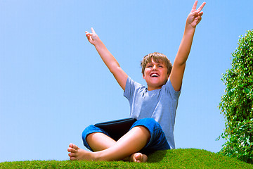 Image showing Happy boy on the grass using his tablet computer