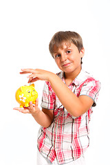 Image showing boy puts the coin into the piggy bank isolated on white 