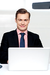 Image showing Attractive smiling man operating a laptop
