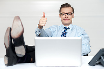 Image showing Thumbs up guy relaxing with legs on work desk