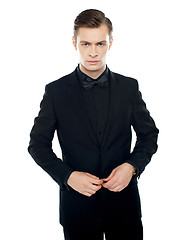 Image showing Serious young man tucking coat button