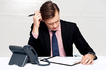 Image showing Confused young man itching his head with pen