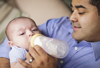 Image showing Happy Hispanic Father Bottle Feeding His Son