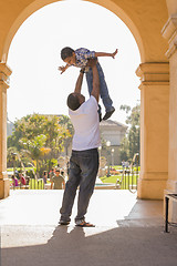 Image showing African American Father Lifting Mixed Race Son in the Park