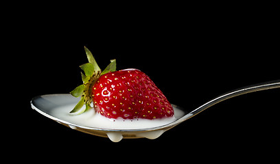 Image showing red, ripe strawberry falling in spoon with milk