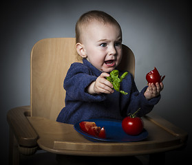 Image showing young child eating in high chair